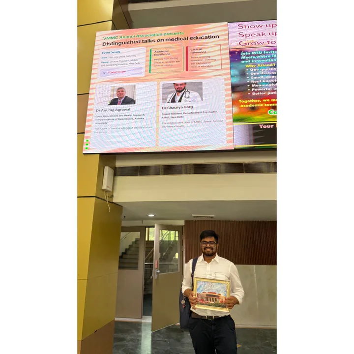 Dr Shaurya Garg beneath the poster for the VMMC Alumni Association distinguished talks